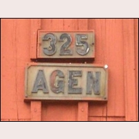 325 Agen har liksom en del andra stugor vid Nordvästra stambanan en speciell typ av nummer- och namnskylt. Den som kommer ihåg hur registreringsskyltar för motorfordon såg ut före 1950-talet känner igen typen. Foto: Jöran Johansson. 
