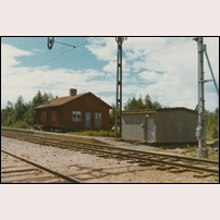 Storträsk station i början av 1970-talet. Ännu ett steg har tagits mot en fjärrstyrd station, i och med teknikhuset tillkommit. Det verkar vara helt nybyggt, marknivån är inte justerad och det ligger en planka som "trappa". Men än finns plattformen kvar som ett minne av den 1969 nedlagda persontrafiken. Bild från Sveriges Järnvägsmuseum. Foto: Okänd. 