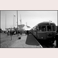 Norrtälje hamn hållplats i maj 1962 anlöps dels av ett rälsbusståg, dels av Silja Lines lilla M/S Nordia. Det var sista året tågen gick hit.

 Foto: Seved Walther. 