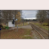 Äskekärr station 2023, en prydlig öppen väntkur har ersatt stationshuset som stod på samma plats. Till vänster om kuren står en gammaldags hästvagn som minne av andra färdsätt. Bild från Google Street View. Foto: Okänd. 