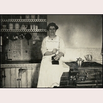 210 Brunnsätra okänt år, troligen omkring 1920. Banvaktshustrun Amalia Hjelmstedt sitter på spiselhällen och maler kaffe medan kaffepannan värms på vedspisen. Bilden är ett bidrag från Kenth Hansson. Amalia var hans morfars mor. Foto: Martin Hjelmstedt, son till Amalia. 
