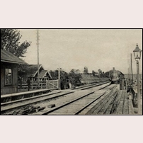 Odensala med tåg på ingång före 1904. Hållplatsen har här sitt ursprungliga läge nära banvaktsstugan 179 som syns bortom den vita grinden. Fotoriktning norrut. Foto: Okänd. 