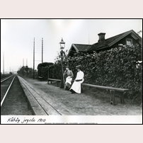 Kåhög hållplats 1910. En lång träplattform låg utanför banvaktsstugan i Kåhög. Sittplatserna var av enklaste slag. Bild från Sveriges Järnvägsmuseum. 		 Foto: Okänd. 