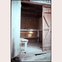 Buddnakk hållplats i september 1993. Sittbänk för resenärernas bekvämlighet finns och en dörr som "nästan går att stänga" (ur en besökares beskrivning av byggnaden). Foto: Lars Holmqvist. 
