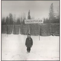 Snasastugan hållplats i februari 1957 med namnskylt och Thomas Welander som representant för ortsbefolkningen.  Foto: C. G. Welander. 