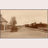 246 Nås 1915, banmästarbostaden ses i bakgrunden till vänster något skymt av det lilla trädet. Byggnaden allra längst till vänster är ett avträde. Godståget dras av lok nr 54, en engelskbyggd maskin från 1899, skrotad 1927. Bild från Sveriges Järnvägsmuseum. Foto: Okänd. 