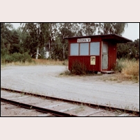 Södra Vi station, väntkuren som fick ersätta det första stationshuset, i juli 1983. Kuren hade ursprungligen tjänat vid Vedemö hållplats på linjen Fornåsa - Motala. Efter tiden i Södra Vi hamnade den i Vena vid Smalspårsjärnvägen Hultsfred - Västervik, där den fortfarande finns kvar (not. 2017). Foto: Sven Olof Muhr. 