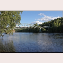 Kvarnsveden, bron över Dalälven den 14 juli 2017. Så mycket mer imponerande är bron sedd från sidan. Vattnet under bron är uppdämt och den fors som fanns från början och som ses på den första bilden är borta. I bakgrunden skymtar den kraftstation som utnyttjar vattnets fallhöjd. Foto: Olle Thåström. 