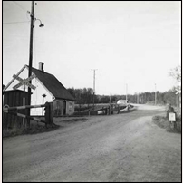 Grindvaktsstugan Stattena 1957. Bilden - från Järnvägsmuseet via www.gammalstorp.se - är tagen av SJ Signalsektion för att dokumentera siktförhållandena i korsningen. Fotoriktning norrut. Foto: Okänd. 