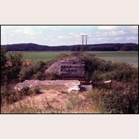 Bron över Stångån finns tyvärr inte kvar, men själva landfästena och banvallen närmast bron ligger väl synliga i det flacka landskapet. Bilden som är tagen mot väster är från den 31 juli 1973. Foto: Jöran Johansson. 