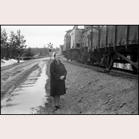 Luleälvsbron 1973, bommarna för landsvägen är fällda så tåget kan passera ut över bron. Brovakten Aina Eriksson granskar tåget för att upptäcka eventuella felaktigheter.  Bild från Järnvägsmuseet. Foto: Seved Walther. 