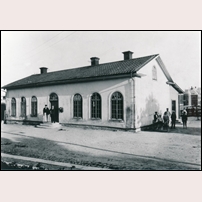 Nora gamla station 1900, samma år som byggnaden revs. I bakgrunden syns det nya stationshuset. Bild från Järnvägsmuseet. Foto: Okänd. 