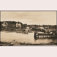 Kvicksundsbron senast 1923 (vykortet postgånget då). Det är alltså den första järnvägsbron som ses till höger. Hästekipage och eventuella automobiler får ännu ett år hålla till godo med den lindragna färjan. Bild från Järnvägsmuseet. Foto: Okänd. 