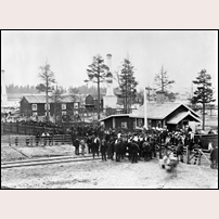 Lerviks grindar banvaktsstuga den 7 juni 1879. Fotografiet är taget vid en demonstration. Skorstenarna i bakgrunden tillhör Sandviks ångsåg. Bild från Järnvägsmuseet. Foto: Okänd. 