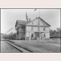 Skyllbergs bruk station 1898. Personalen står uppställd vid det dekorerade stationshuset, det är dags för besök av kung Oscar II. Bild från Järnvägsmuseet. Foto: Okänd. 