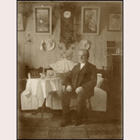 Banvakten Gustaf Pettersson omkring 1905. Bilden är tagen i hans bostad, men om det är i banvaktsstugan Båstadsängen eller i hans pensionärsbostad i Solberga är omöjligt att avgöra, Bild från Järnvägsmuseet. Foto: Okänd. 