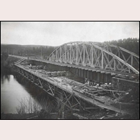 Den ursprungliga fackverksbron över Lagan visade sig snart för svag och en ny bro med tre plåtbalksspann ersatte den gamla. Här har den gamla bron skjutits åt sidan och den nya bron lagts på plats. Bytet skedde den 18-19 november 1920. Bild från Järnvägsmuseet. Foto: Okänd. 