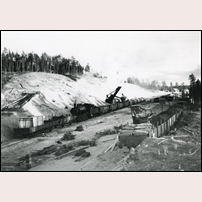 Vaimats grusgrop 1936. Ett nio vagnars tågsätt får påfyllning innan det backas ut ur gropen fram till lokstationen. Där kan rundgång göras, så att loket kommer i rätt ände av tåget för fortsatt färd ut till huvudlinjen. Foto: Ludvig Wästfelt. 