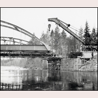 Bro över Voxnan den 30 oktober 1961. Den gamla bron har forslats åt sidan och den nya är på väg att lyftas på plats. Bild från Järnvägsmuseet. Foto: Okänd. 