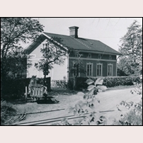 Svanå station den 13 juni 1944. Hästen förspänd en enaxlig kärra väntar utanför medan kusken gått in för att uträtta något ärende. En damcykel är parkerad i cykelstället av trä. Några mjölkflaskor står i skuggan intill häcken skyddade från solens värme och väntar på vidare transport. Inga människor finns inom synhåll. En annan tid, en annan miljö. Bild från Järnvägsmuseet. Foto: Okänd. 