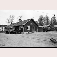 Ljusfallshammar station den 19 maj 1965. Fyra år efter att den föregående bilden togs och tre år efter att persontrafiken lagts ned är det mesta förändrat. Posten och Postsparbanken har lämnat stationshuset och skyltarna tagits ned liksom den gula brevlådan Förmodligen har posten övergått till lantbrevbäring, en förändring inte bara till det sämre. Tidtabellstavlan har tagits bort, och dörren till väntsalen är stängd. Ändå står sittsoffan kvar utanför, som ett slags efterklang av bekvämlighet för dem som nu väntar på bussen.
På spåret intill lastbryggan står en lastbil från SLAB — SJ:s eget lastbilsbolag — som nu tar över styckegodset. En modern landsvägsbuss väntar på andra sidan stationshuset. Ett stångkoppel till en överföringsvagn ligger kvar på spåret — en teknisk detalj som vittnar om hur godstrafiken en gång krävde samspel mellan smalspår och normalspår. Det gamla stationshuset har blivit ett tyst vittne till en tid som just runnit undan. Ändå är stora förändringar att förutse. Stationshuset kommer snart att rivas och riksväg 51 dras över dess tidigare plats och några år ska hela järnvägen rivas upp. Ingenting ska längre minna om hur järnvägsstationen en gång var bygdens hjärta.
 Foto: A-P Jonasson. 
