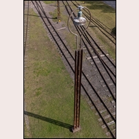 Vadstena station den 5 september 2025. En lyktstolpe visar sig vara sammansatt av två s.k. Batesstolpar. Fotografen uppger att de med 99,9 % säkerhet köptes från Nordmark - Klarälvens järnvägar som en del av deras beställning från USA. De användes, en och en, vid NKlJ för att uppbära kontaktledningen. Kanske begagnades de på samma sätt i Vadstena, linjen Linköping - Vadstena var ju elektrifierad under åren 1921 - 1956. Foto: Peter Berggren. 