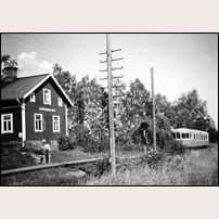 Svenneby hållplats med ett av de sista tågen innan trafiken lades ned från och med den 1 september 1960. Mannen med den lille gossen intill sig är förmodligen sysselsatt med att manövrera den elektrisk påstigningssignalen på hitsidan av sppåret. Många telefontrådar är det fortfarande i bruk. Bilden förmedlad av Jan-Anders Wihrén. Foto: Einar Pettersson, Vadstena. 